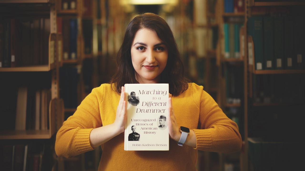 Niloufar Mansooralavi holding a book in the library 