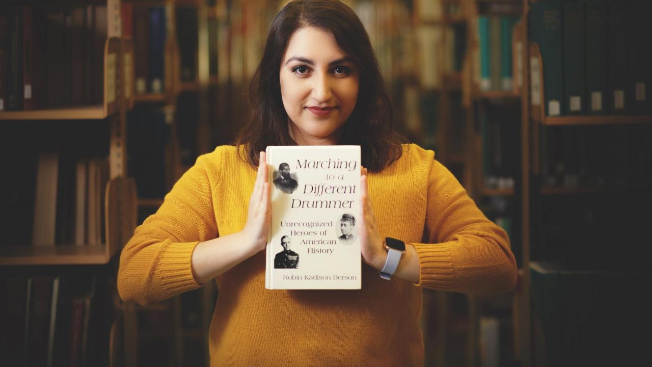 Niloufar Mansooralavi holding a book in the library 