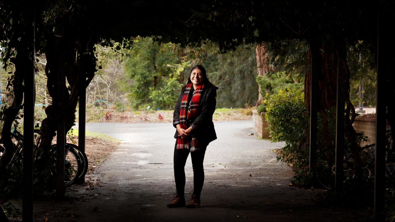 First-gen student, Lucero Morales, standing in the arboretum 