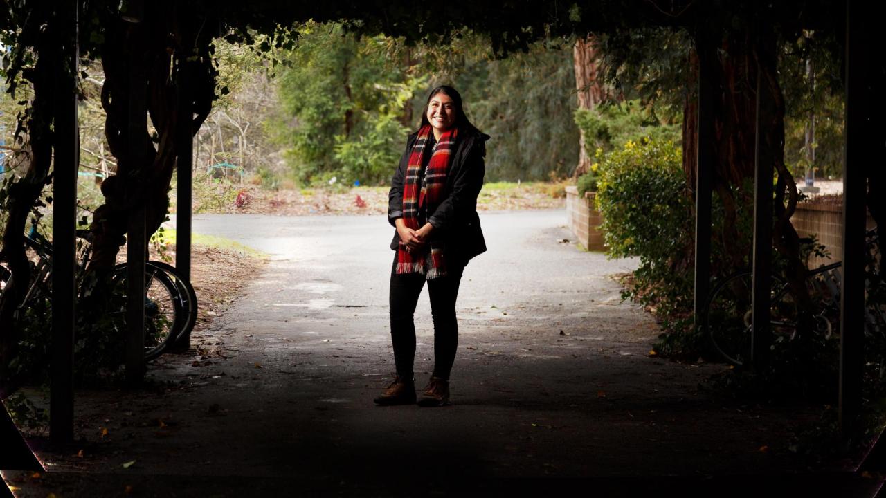 First-gen student, Lucero Morales, standing in the arboretum 