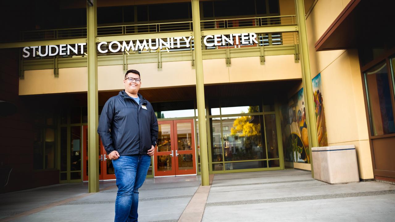 First Generation College Student Dave Ivan Cruz stands in front of the Student Community Center (SCC).