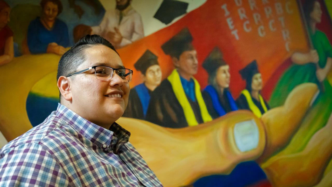 E. Nunez stands in front of the mural of the Student Community Center.