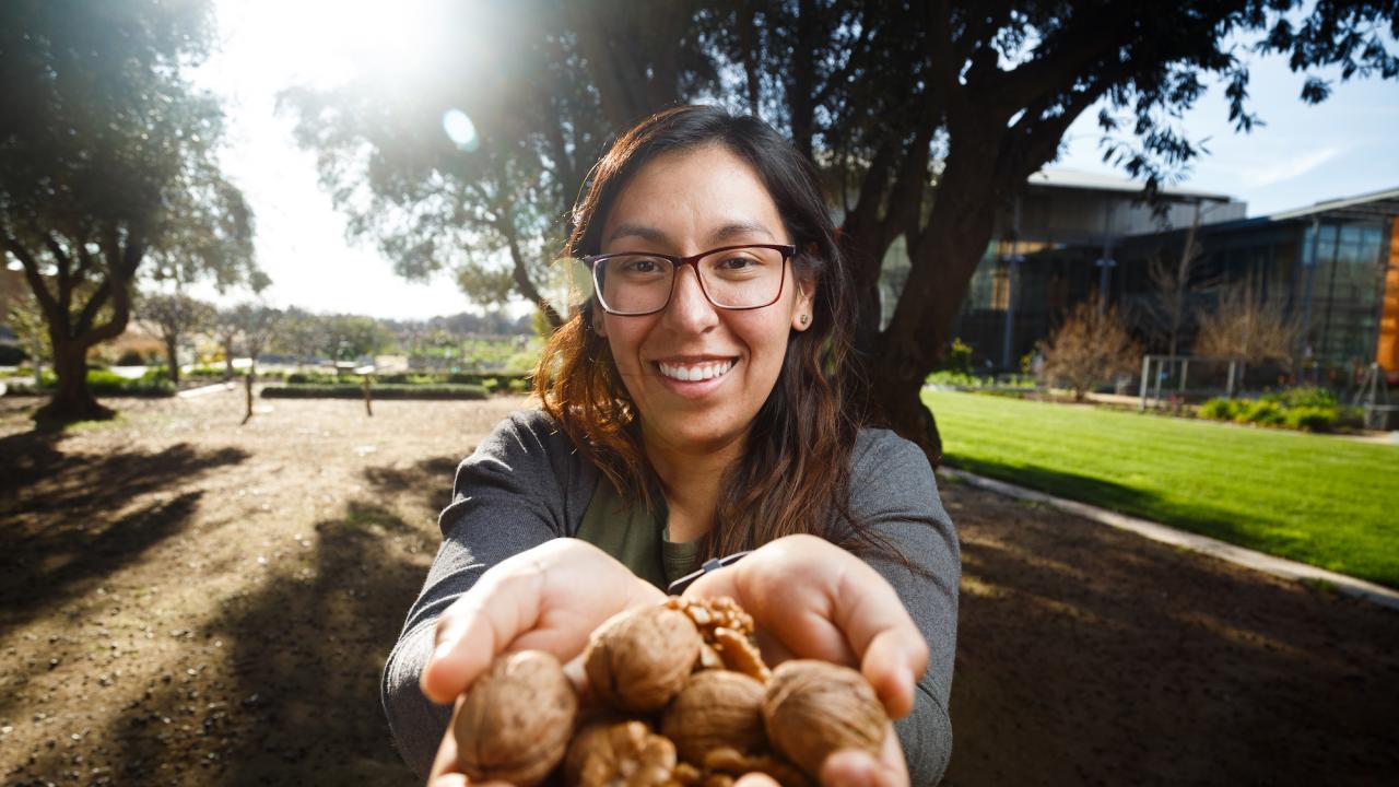 Erika Estrada offering walnuts outside the Mondavi Institute